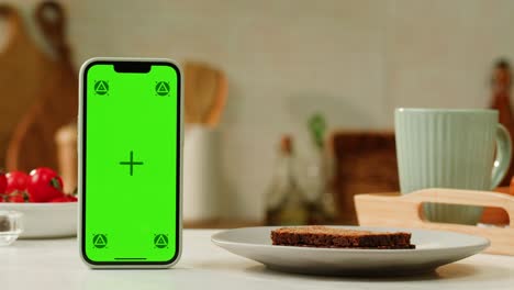smartphone with green screen on kitchen table with bread