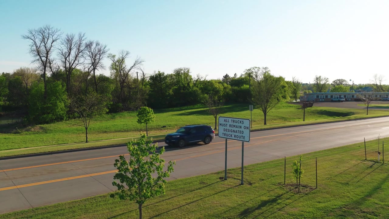 Designated truck route sign along an empty Jamestown ND highway. Aerial view of commercial rural infrastructure in North Dakota without people during a sunny golden hour.