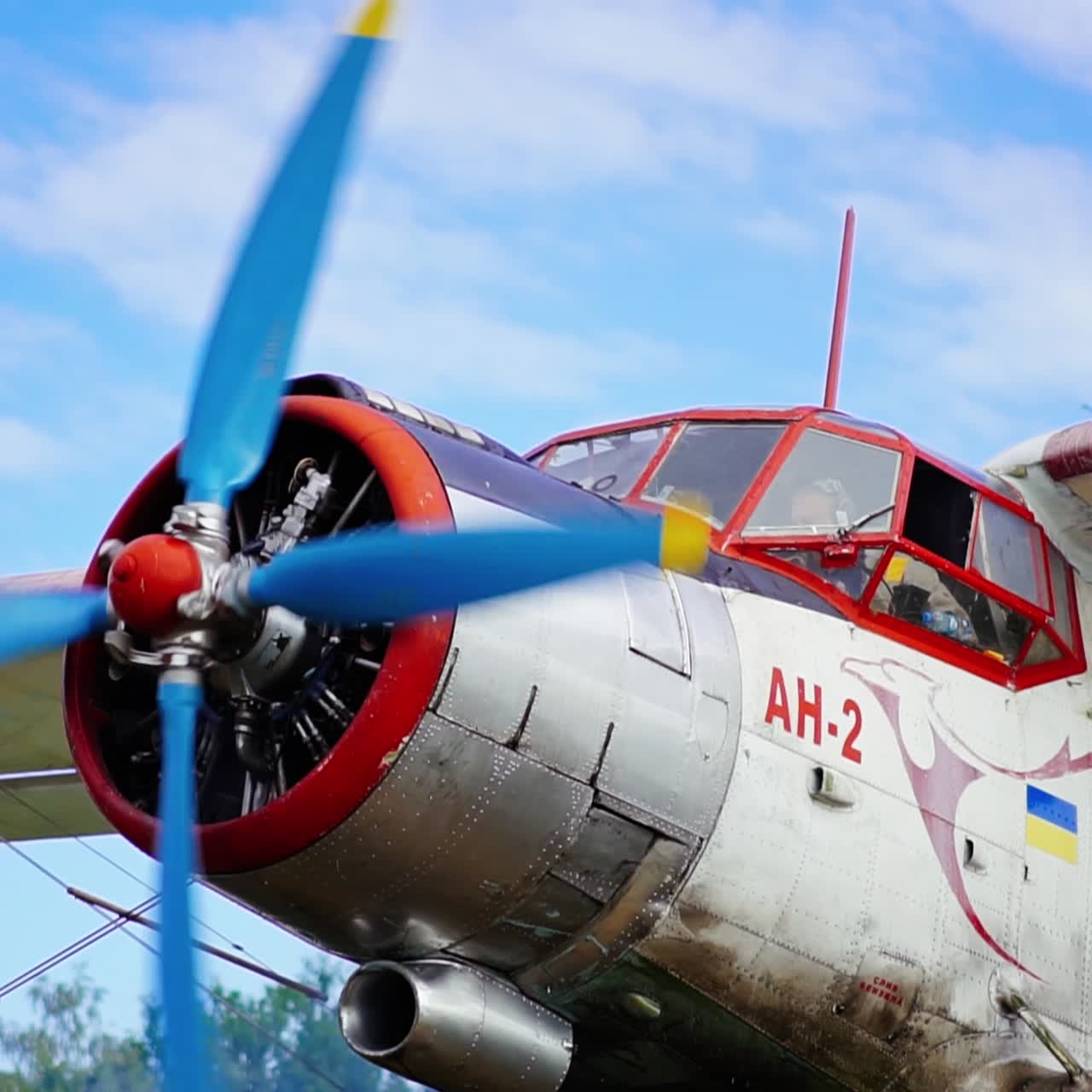 Aircraft with a pilot sitting in the cabin. The airplane propeller start to move. Low angle view