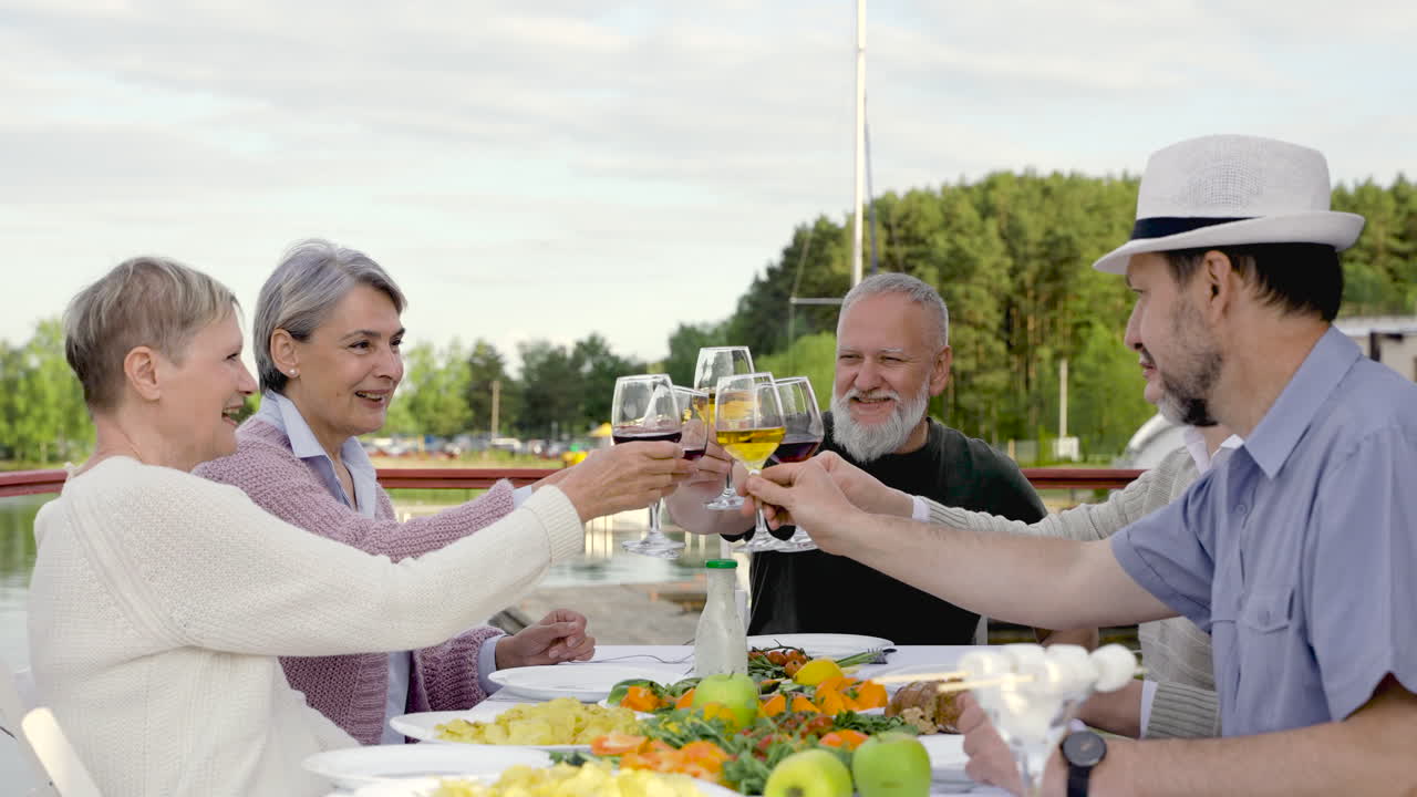 un grupo de personas mayores están cenando, brindando y bebiendo
