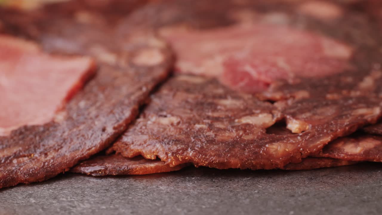 black bull sausage ham, tongue pork dry-cured sausage on a black background, traditional spanish delicatessen food, close up.