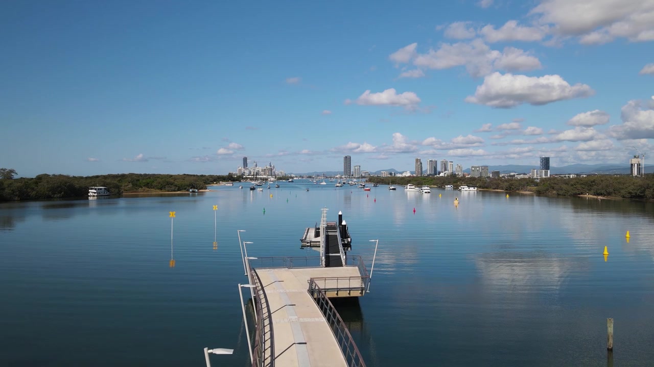 Vista creativa da drone che si muove lungo un pontile pedonale di marina di nuova costruzione che porta a una vista dello skyline della città