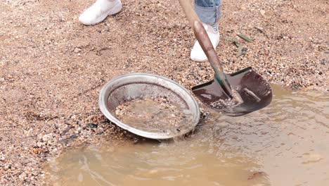 person panning for gold in muddy water