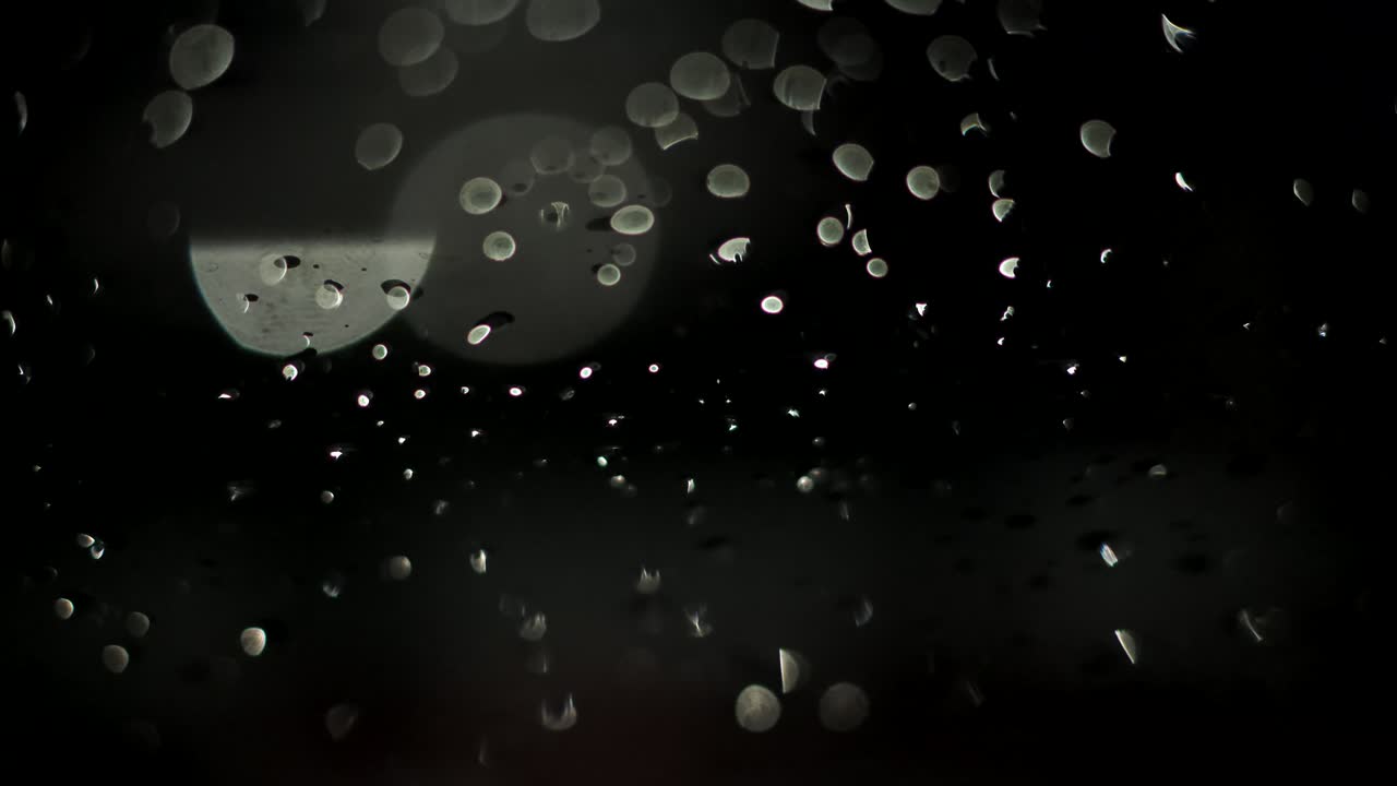 Raindrops at night creative footage black background. Rainy weather. Take one.