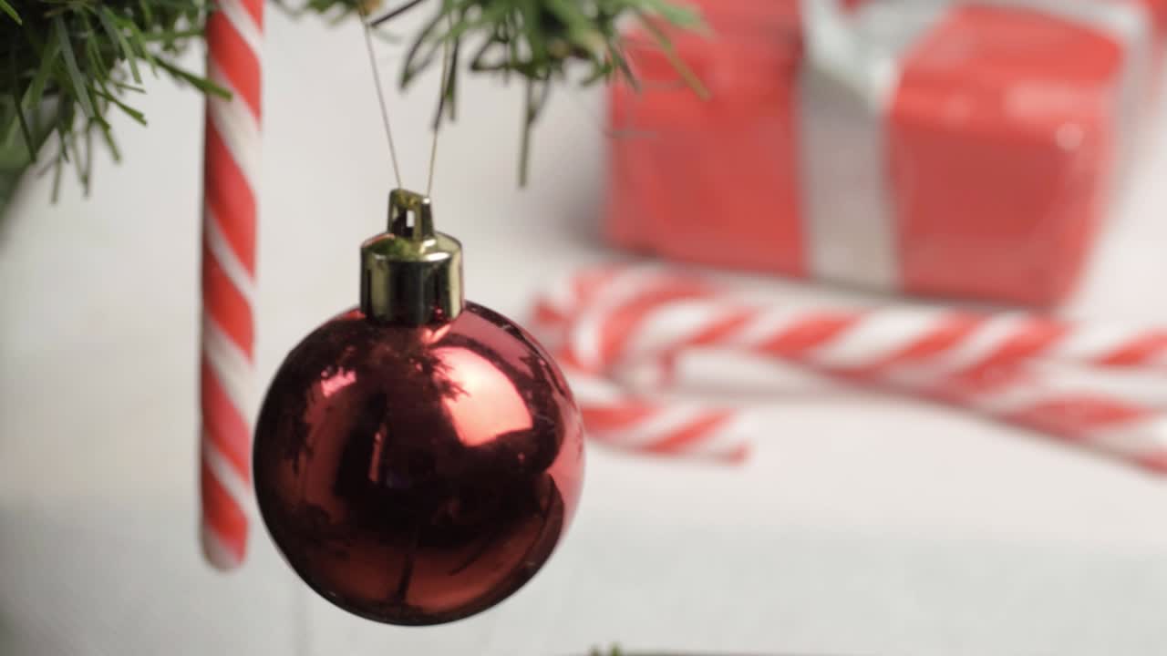 Christmas bauble hanging with candy canes and gift background
