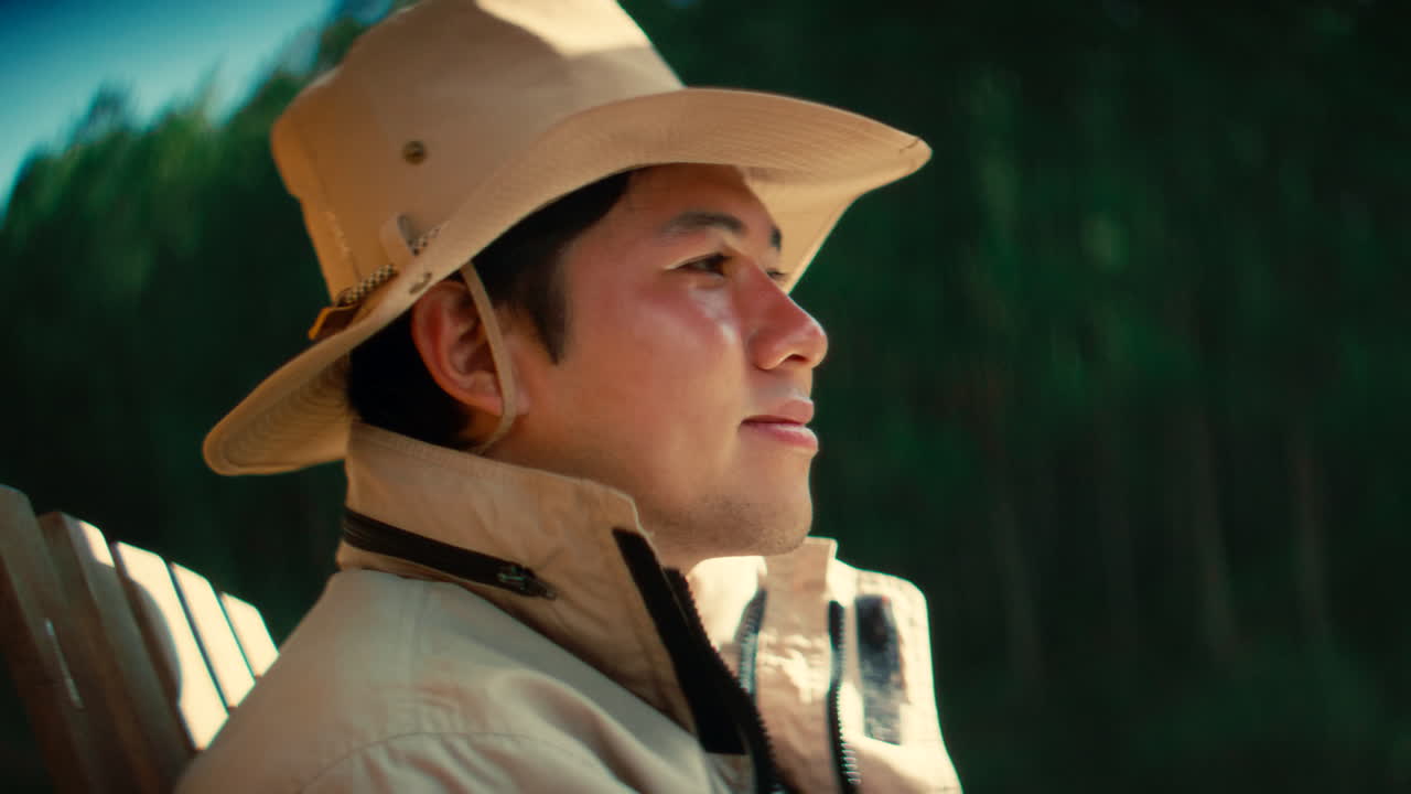 Man in a hat sitting in a chair in a forest