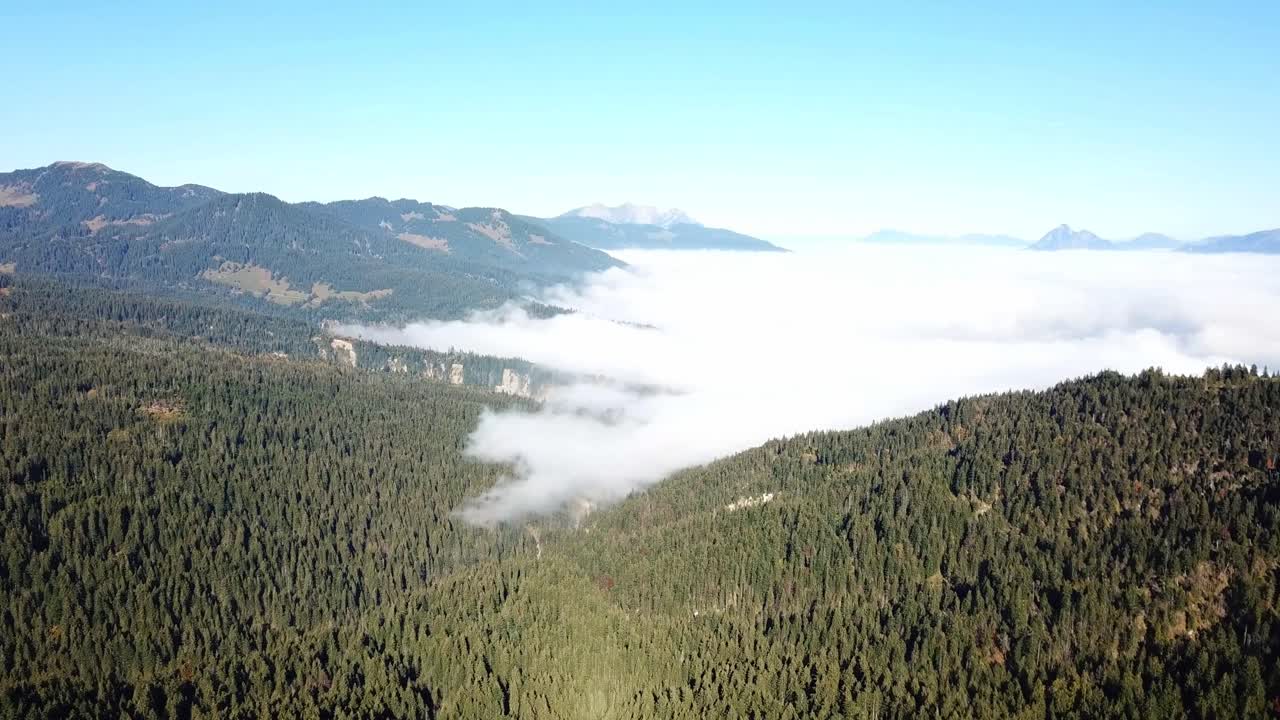 Panoramic view over Panoramastrasse at Glaubenbielen Pass in Obwalden, Switzerland, with mountains and valley under clear sky as fog or cloud cover spreads above forest