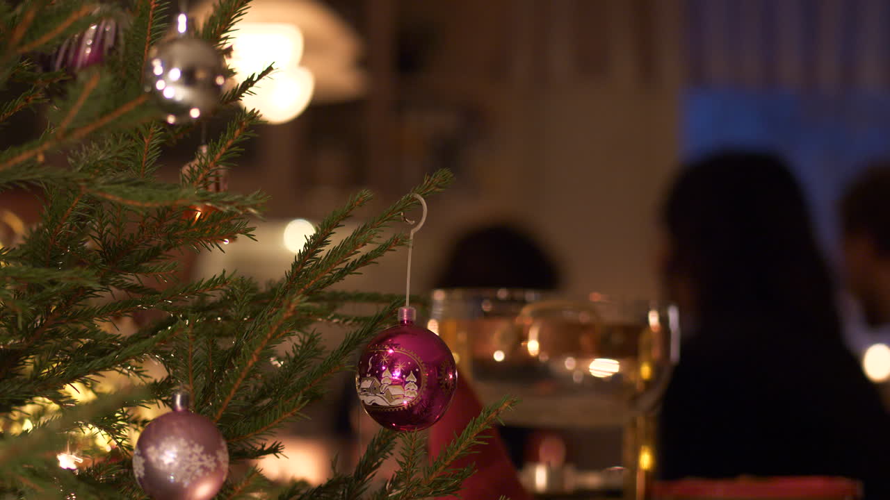 Decorated Christmas tree and family gathered at Christmas dinner table