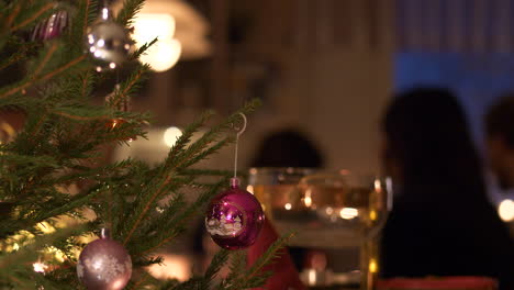 decorated christmas tree and family gathered at christmas dinner table