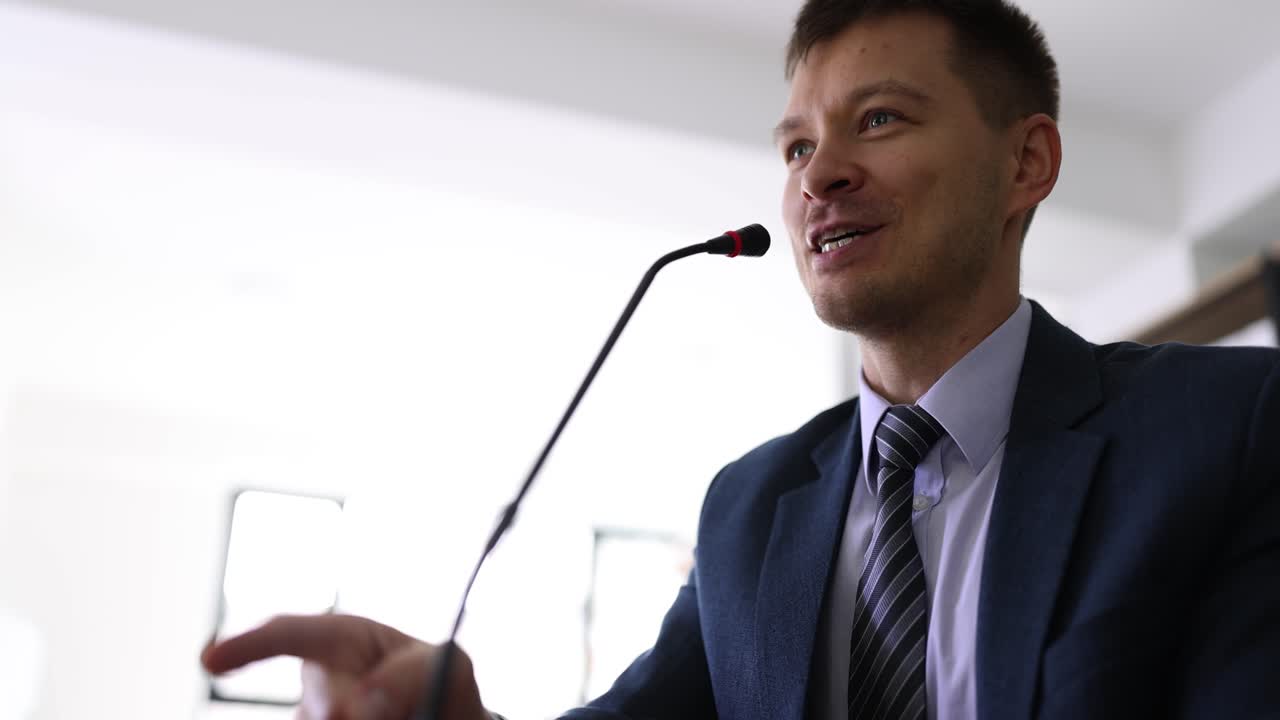 Man speaking into a microphone at a conference or presentation