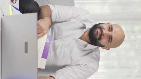 Vídeo-Vertical-De-Un-Trabajador-De-Oficina-En-Casa-Leyendo-Un-Libro.