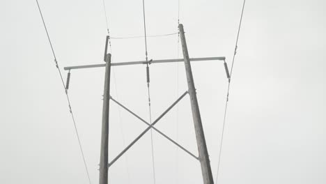 tracking shot of a tall wooden hydro pole with 5 ines