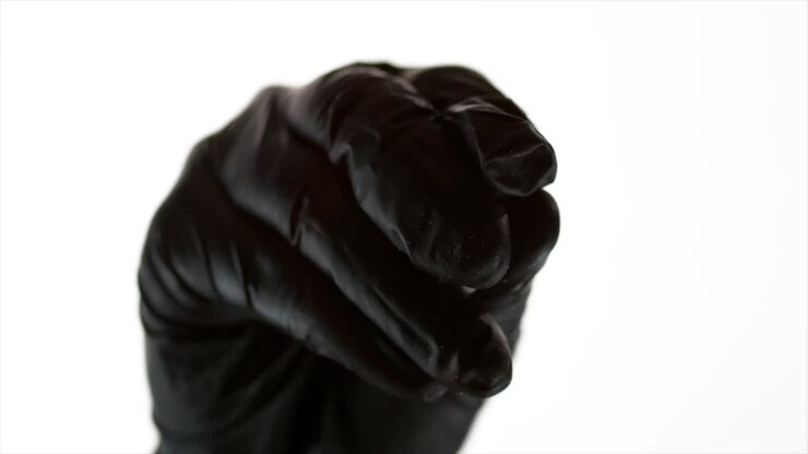 Close up of hand with black glove sprinkling sea salt towards camera