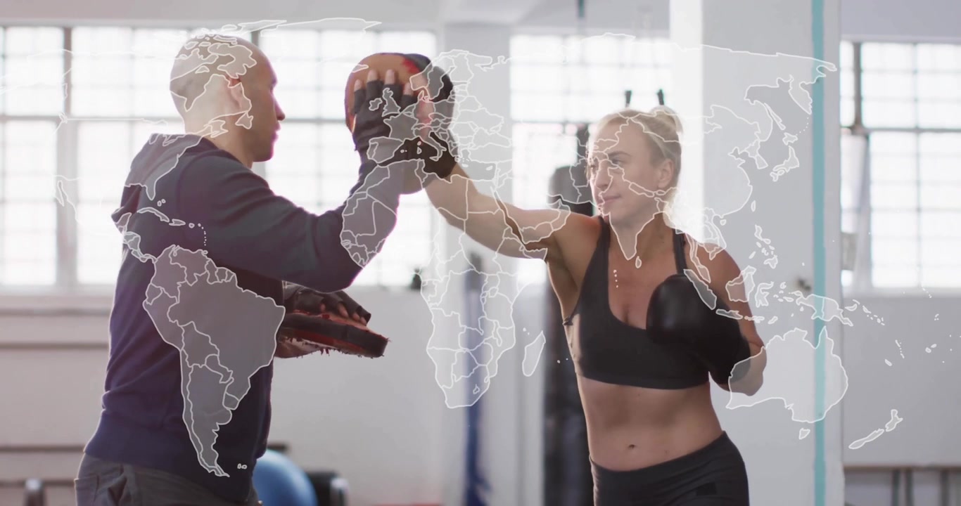 Treinador de fitness levantando manoplas na altura da cabeça e da cintura enquanto atleta soca aparadores de soco em treino de boxe.
