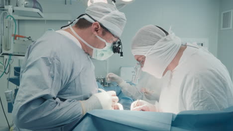 surgeons with micro forceps operate. skilled medics in sterile uniform use instruments for working on small coronary arteries in operating room