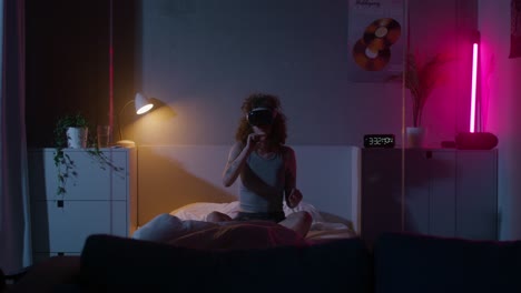 mujer con auriculares vr en un dormitorio por la noche