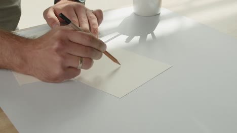 the designer draws a sketch on the white cardboard with a pencil - the packaging design process.