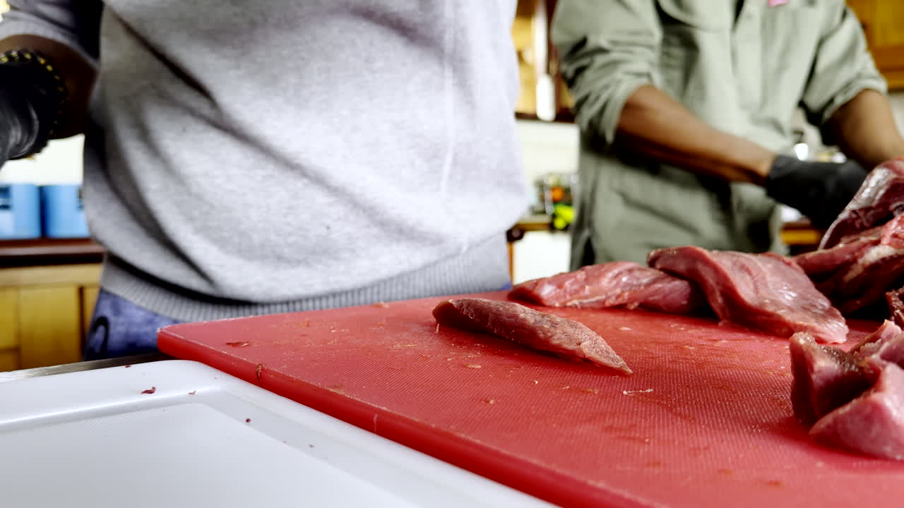 African chef carefully trims raw meat with skilled precision, closeup