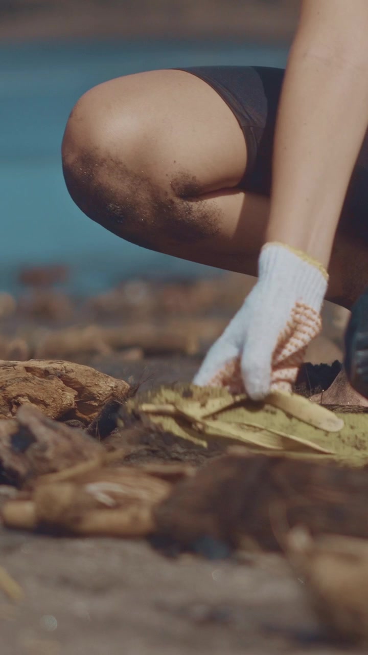 Close up of a volunteer on a beach picking up a discarded plastic with a gloved