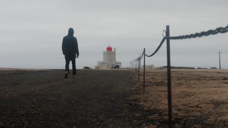 person walking towards lighthouse in iceland