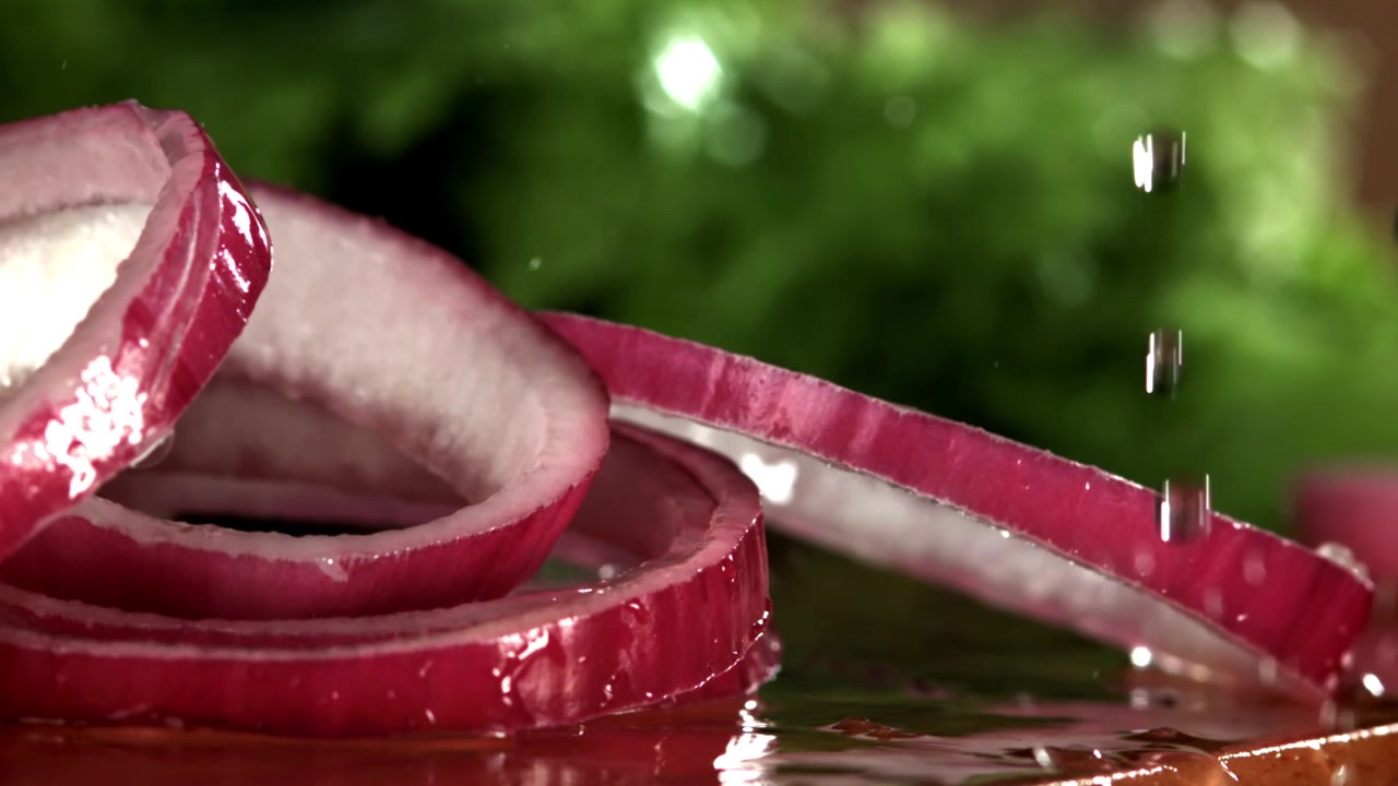 Red Onion Rings Falling and Splashing into Water in Slow Motion