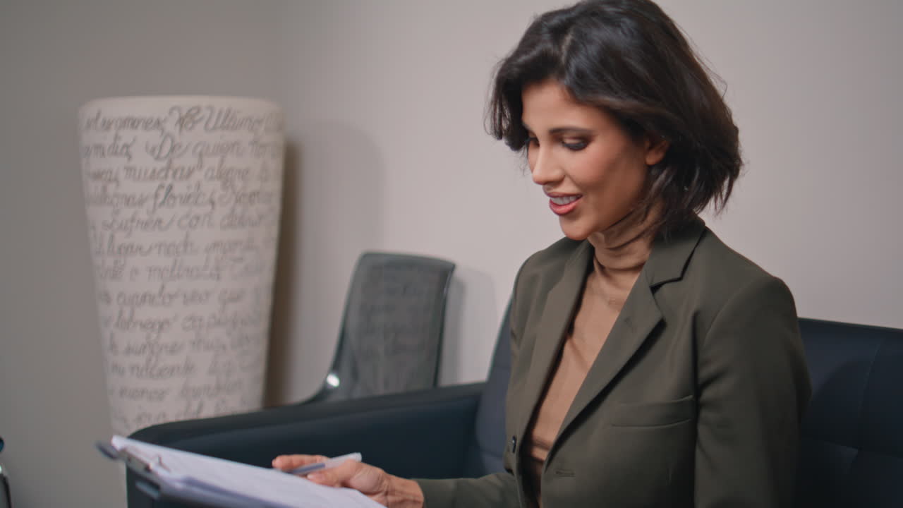 Clinic client taking document from specialist for signing on sofa lobby closeup