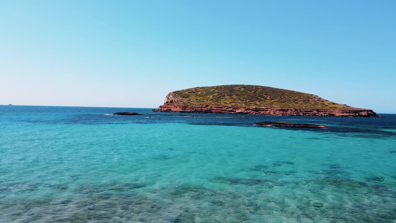화창한 날 이비자에 있는 칼라 콤테의 청록색 푸른 물 위로 날아가는 공중 전망