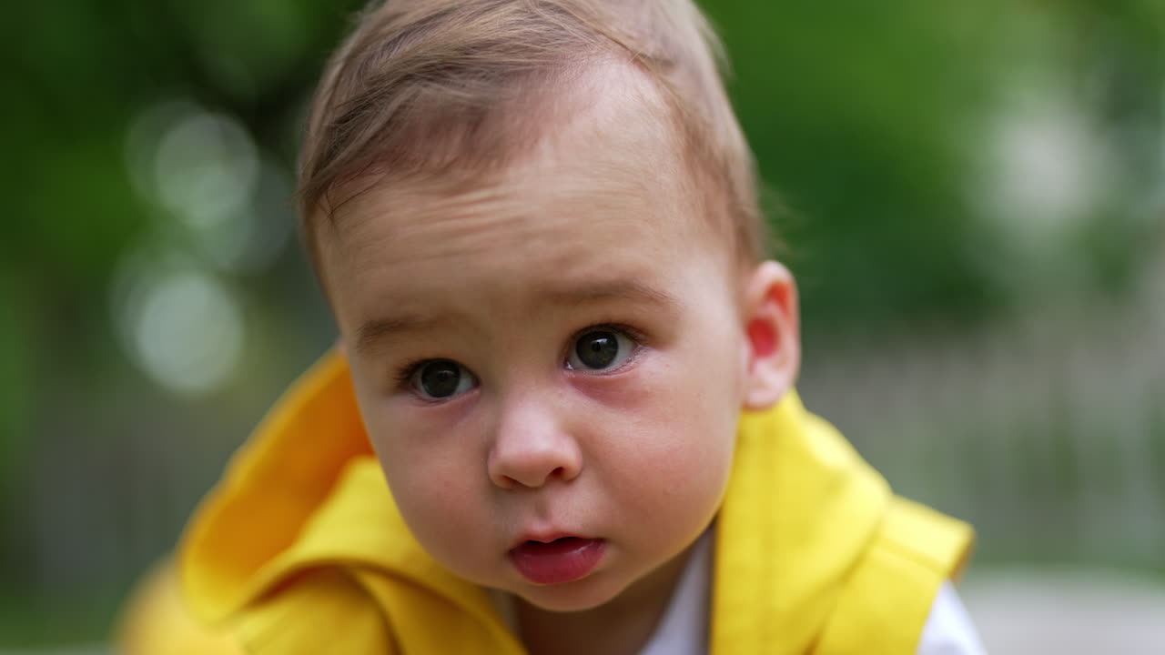 Little adorable Caucasian baby boy spending time outdoors. Calm cute toddler looking straight into camera. Close up.