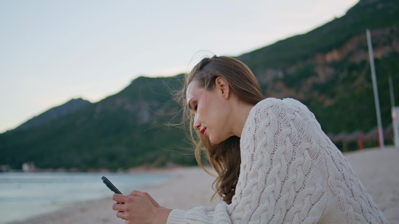 Vacation woman using smartphone for online communication at ocean shore closeup
