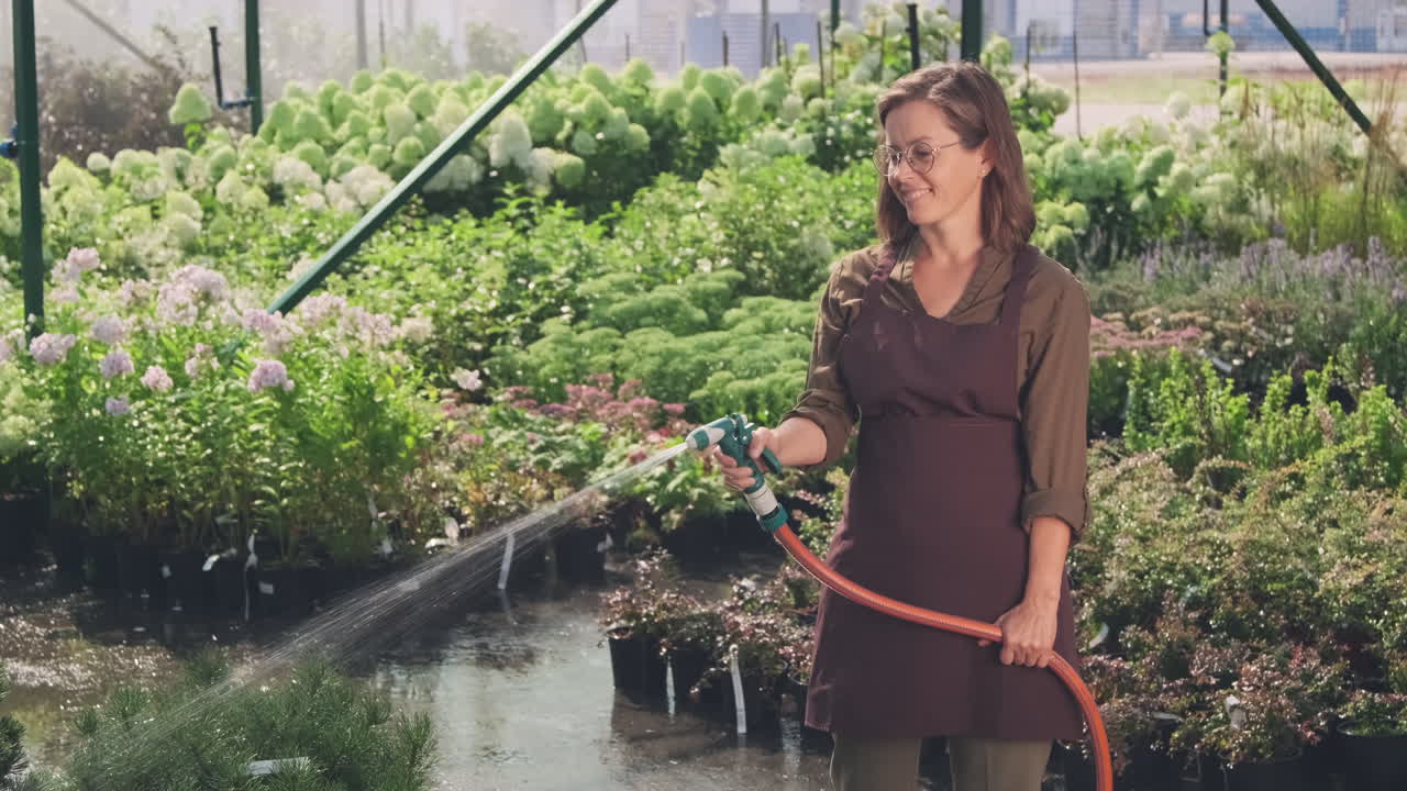mujer regando plantas en el invernadero