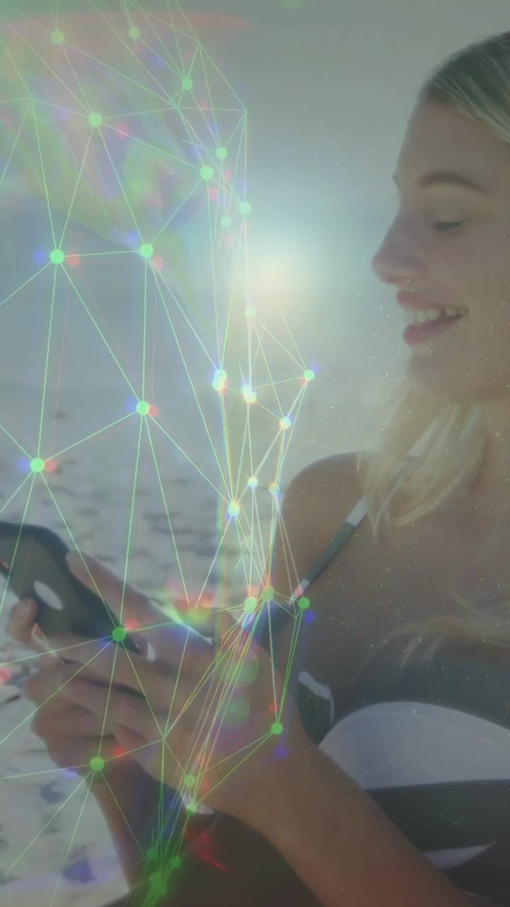 Video vertical: Mujer tocando el teléfono en la orilla, activando una superposición de red sobre sus manos para tecnología móvil.
