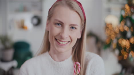 beautiful woman holding candy cane during christmas at home