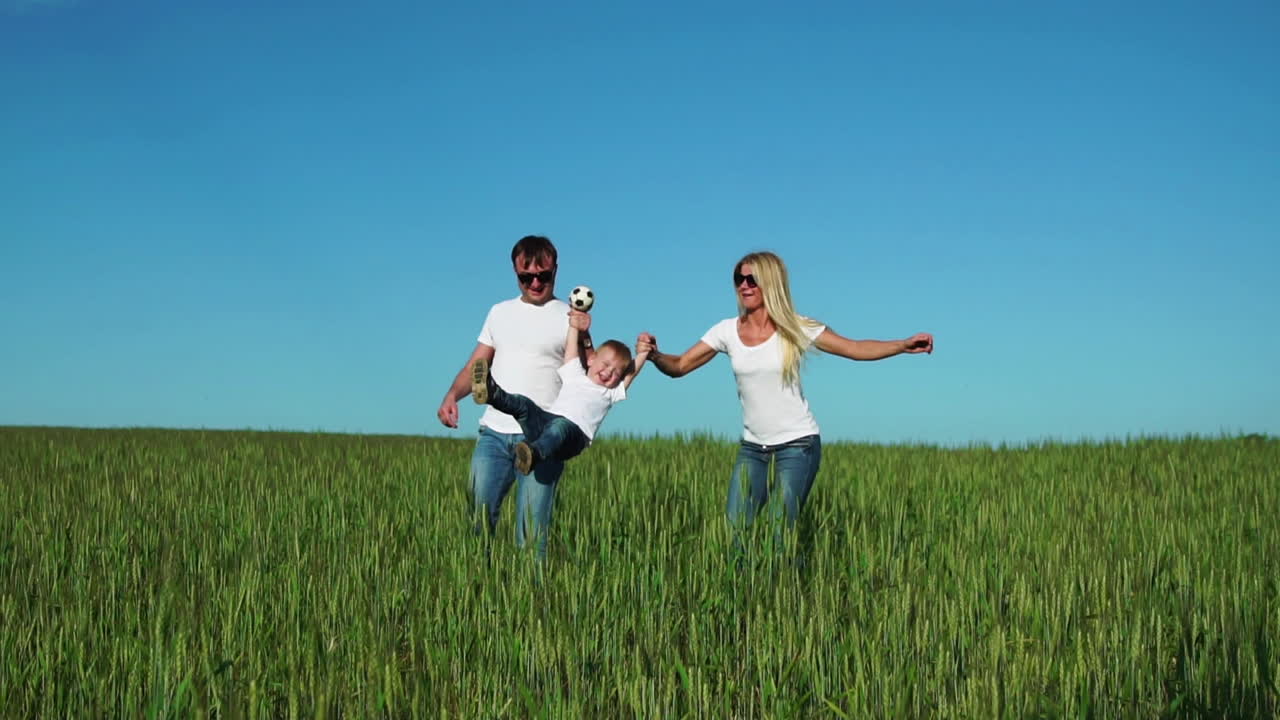 familia feliz: padre, madre e hijo, corriendo en el campo vestidos con camisetas blancas