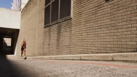 african american woman exercising outdoors running next to bridge in the city