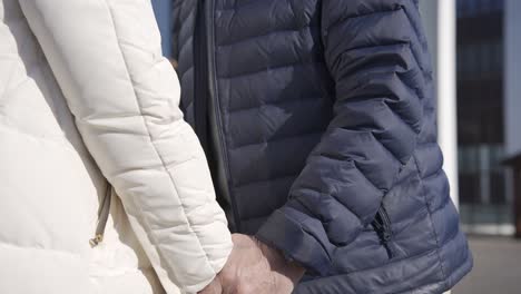 close-up view of the senior couple holding hands on a winter day