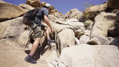 young caucasian backpacking adventurer climbing rock mountains in canary island, spain travel holiday trekking destination, wide angle looking up shoot