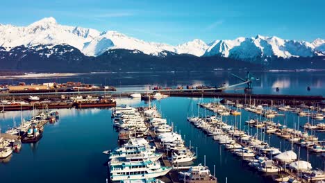 4k drone video of seward boat harbor and surrounding snow covered mountains on snowy winter day in alaska