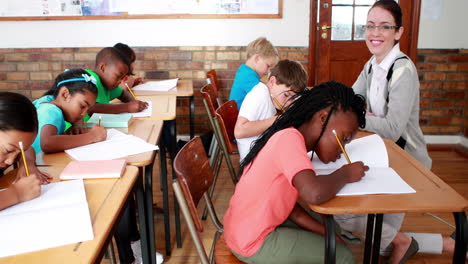 Pupils-working-hard-during-class-with-teacher-smiling-at-camera