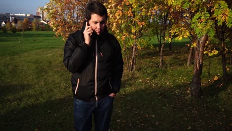 hombre hablando por teléfono en el parque de otoño