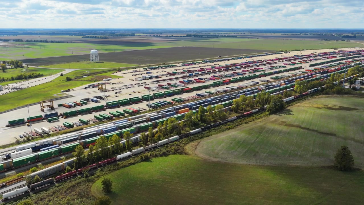 Weitläufiges Luftpanorama des Union Pacific Containerterminals und des umliegenden Ackerlandes, Drohne, Wolkenschatten ziehen über Grasfelder