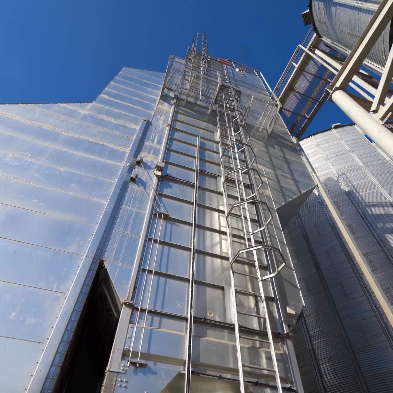 Industrial part of manufacture at sunlight. Modern industrial plant on blue sky background. Exterior of a new building for agribusiness