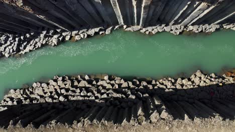 ascending aerial top down of spectacular rocky ravine with green water lighting by sunlight - stuðlagil,iceland