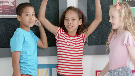 biracial boy and girls, one caucasian and one biracial, smile in classroom