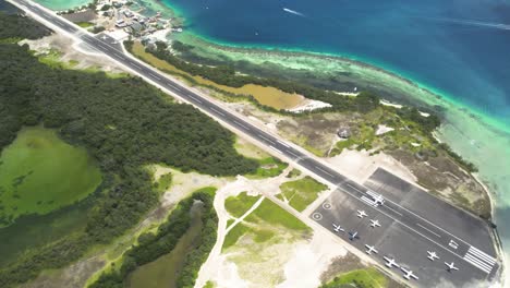 los roques' landing strip by clear turquoise waters and lush greenery, bright daylight, aerial view