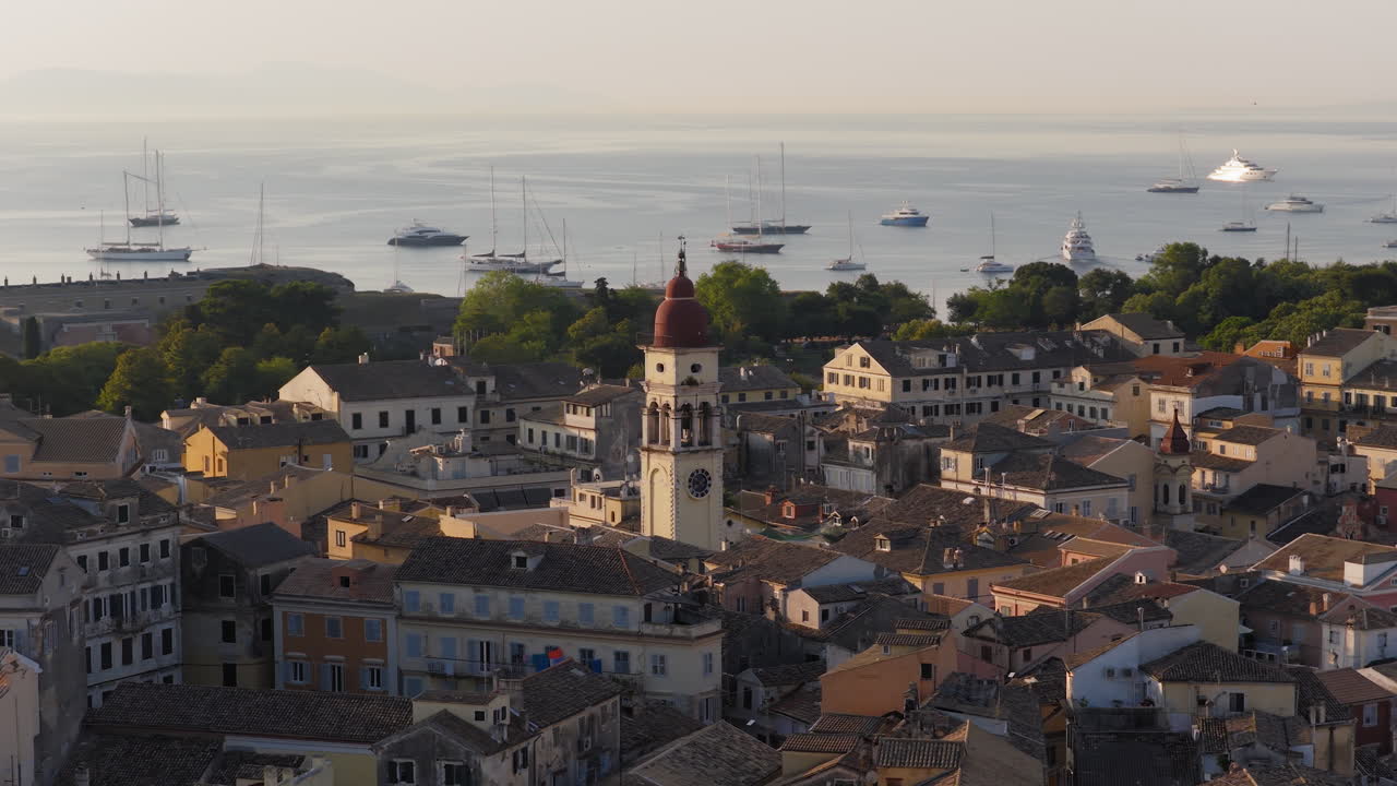 Sunrise over Corfu rooftops and Saint Spyridon Church with swallows circling above, medium drone orbit