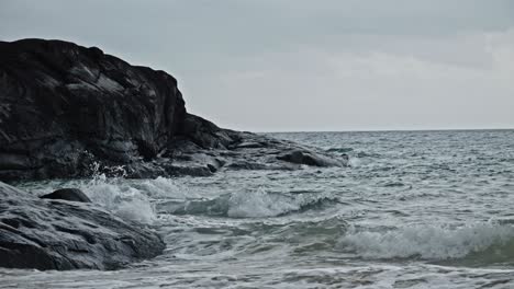 Toma-En-Cámara-Lenta-Desaturada-De-Rocas-Y-Olas-Ondulantes-Del-Océano-En-Dam-Trau,-Isla-Con-Dao,-Vietnam