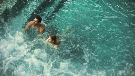 Attractive-couple-relaxing-in-whirlpool-bath.-Lovely-couple-swimming-in-pool