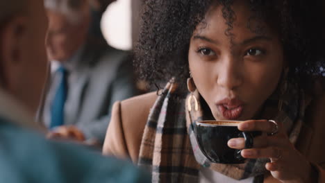 happy african american woman chatting with friend in cafe drinking coffee laughing enjoying gossip conversation hanging out in busy restaurant for lunch meet up