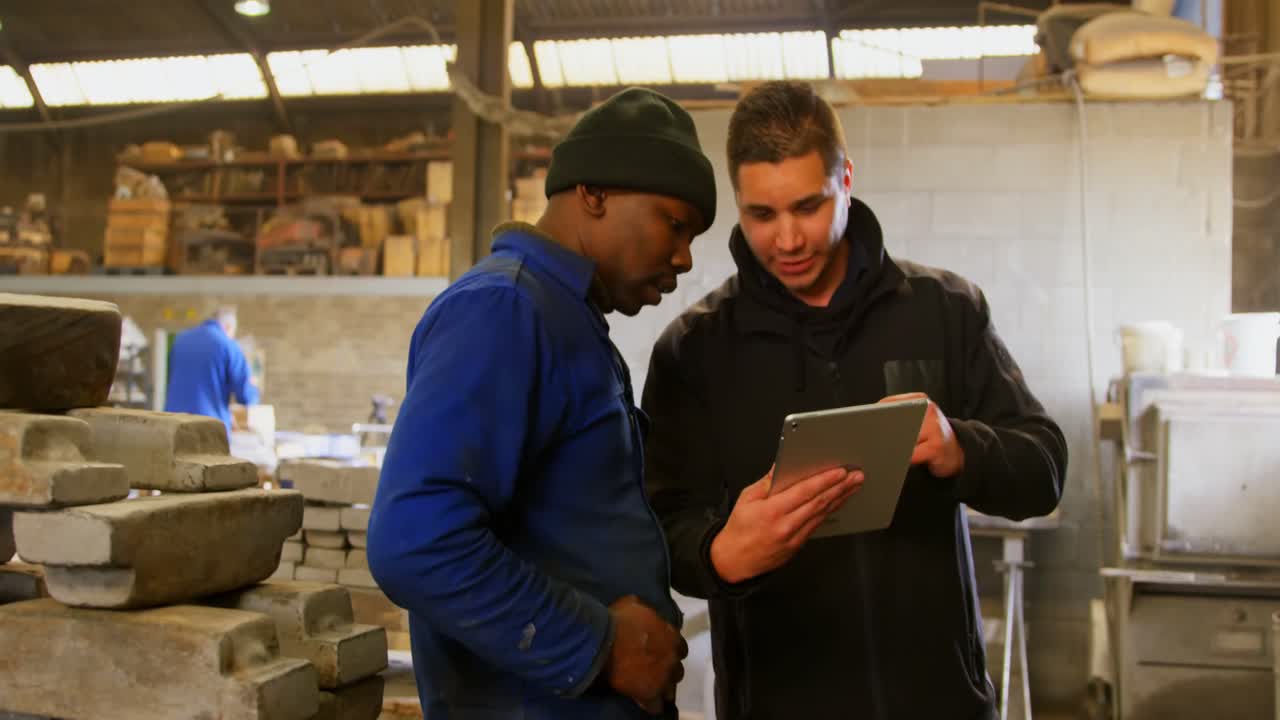 Workers discussing over digital tablet in workshop 4k