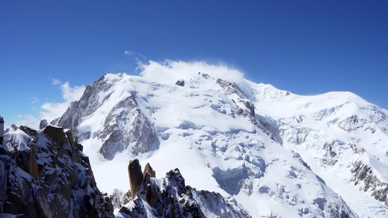 snow covered rocky peaks of the alpine mountains. Mont Blanc mountain in a cloud against a blue sky